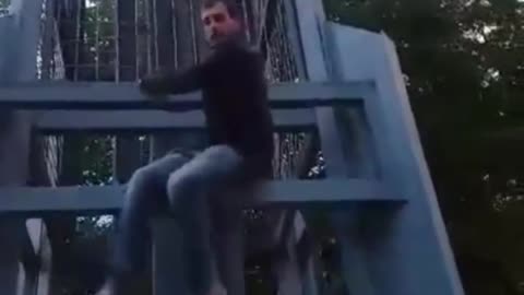 Plaid shirt guy jumps off metal statue falls down