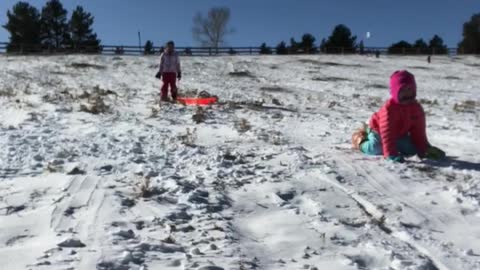 Mom on sled with little girl in pink gets dropped off in snow