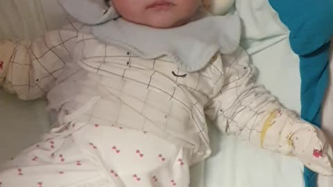 The baby is raising his head to see the hand movements of an adult Baby smiling happily