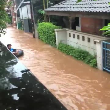 Kid floats down tube in flooded streets of Jakarta