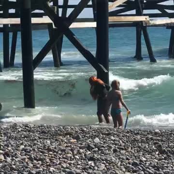 Woman with red hair dancing on beach filmed buy her friend