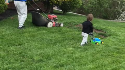 Toddler Follows Dad's Lead in Mowing the Lawn