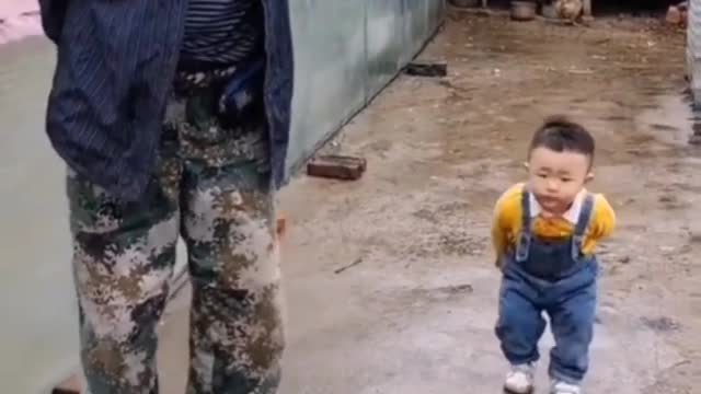 An astonishing baby walk like his grand father with his hand to back and bend his knee