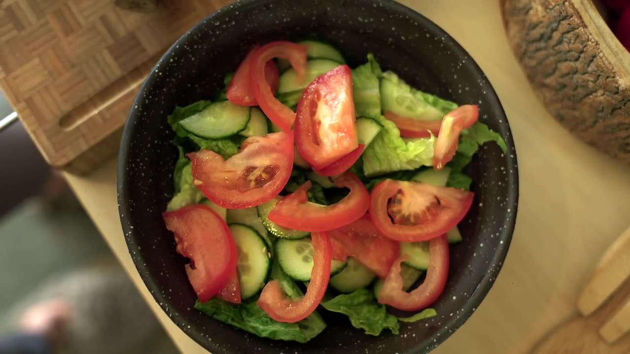 Close Up of Female Hands Adding Sliced Tomato to Salad Bowl