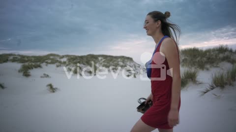 Young woman walks at a white sand beach wearing a red