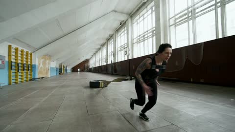 A Woman Doing Extreme Exercise, By Pulling A Tied Tire Attached To Her Body