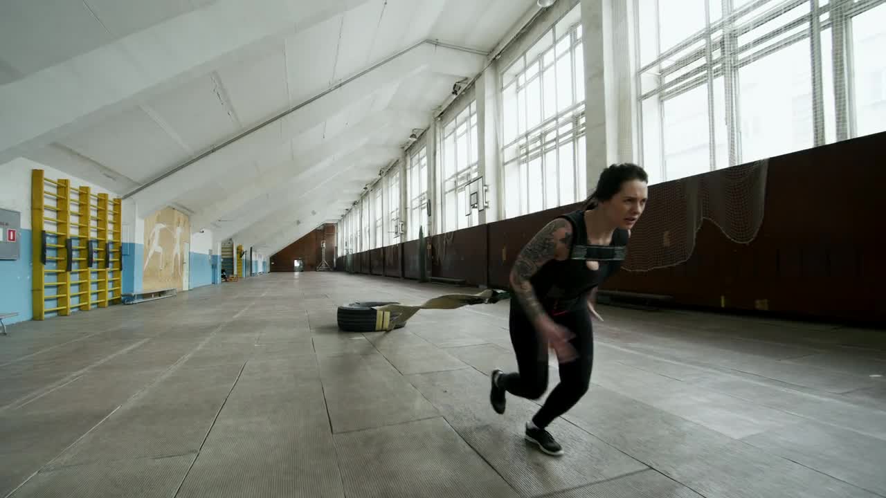 A Woman Doing Extreme Exercise, By Pulling A Tied Tire Attached To Her Body