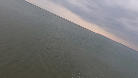 Panning away from the sea to the beach. Drone footage