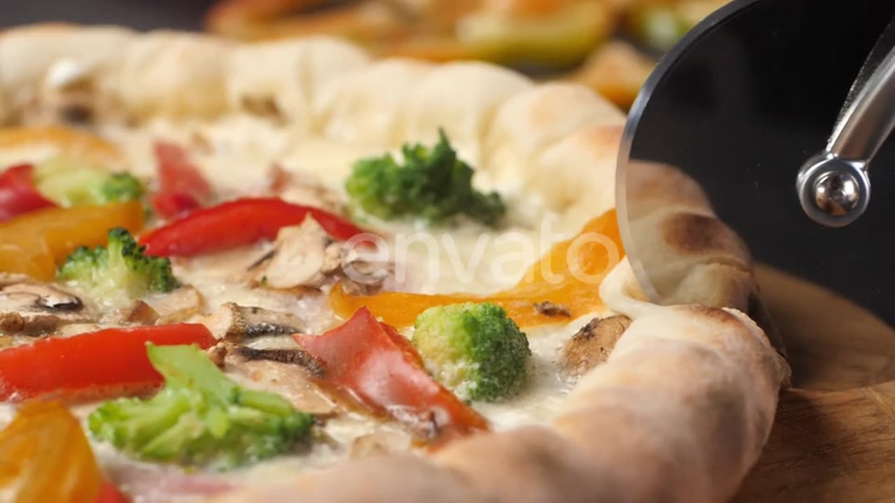 A Pizza Knife Rolls Over the Surface of a Fresh Pizza Cutting It