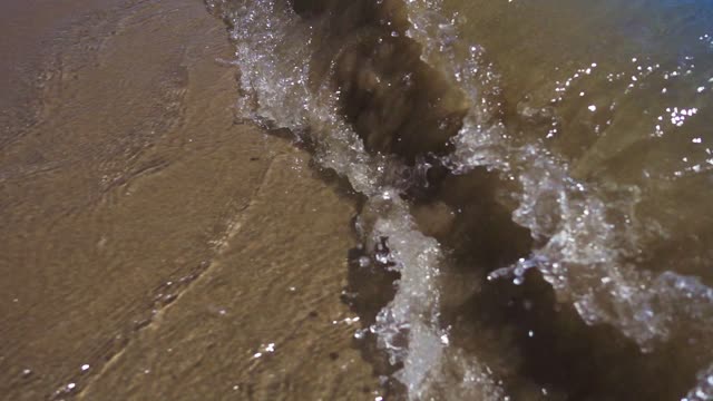 The clear sea water rushes towards the shore