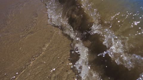 The clear sea water rushes towards the shore