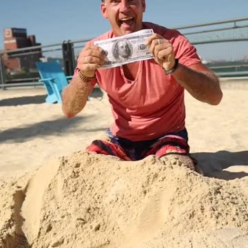 A Man Digging Money From The Sand