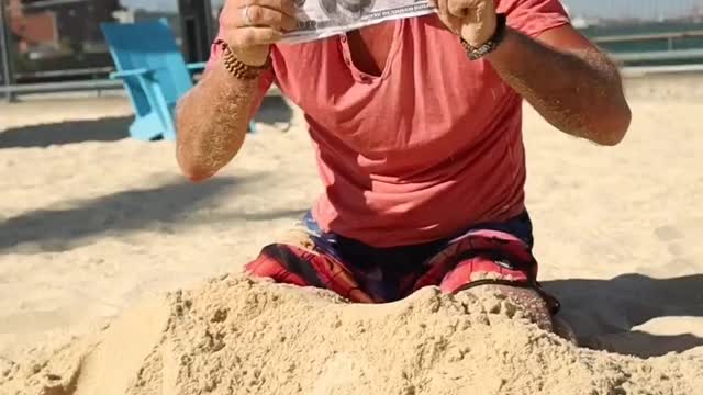 A Man Digging Money From The Sand