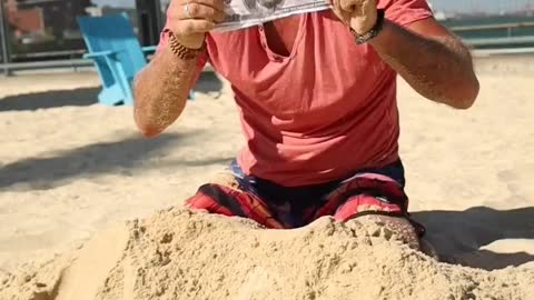 A Man Digging Money From The Sand