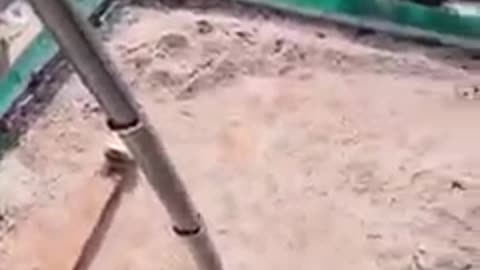 Crane lifting a backhoe onto a top of a skyscraper