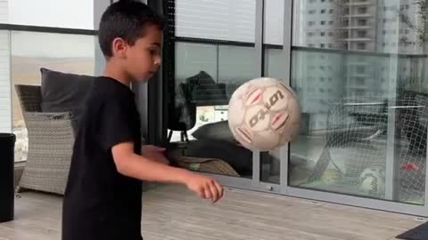 Kid Displays Talent by Balancing Football Over Himself While Picking Up Cones From Floor