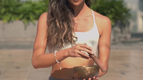 A Woman Meditating while Using a Healing Bowl