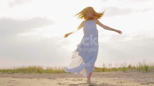 carefree-woman-dancing-on-the-sunset-on-the-sea-beach-girl-spinning-video-id1168549671.mp4