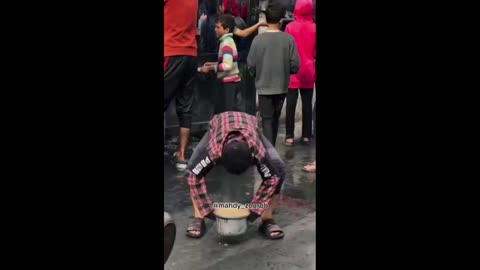 Dozens of displaced Palestinians crowd to fill their pots with food