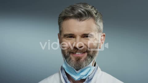 Portrait Of The Young Happy Man Physician Taking Off Mask From His Mouth And Smiling Cheerfully