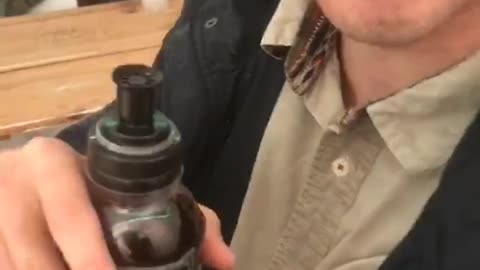Guy holding bottle with dark liquids makes weird sounds and faces
