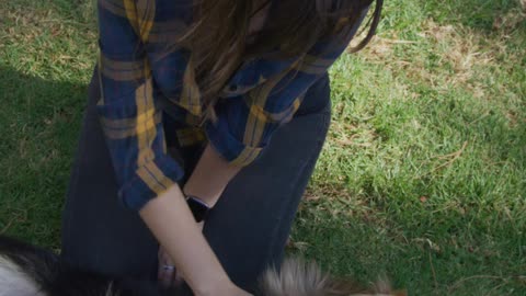 Woman petting her dog on the lawn