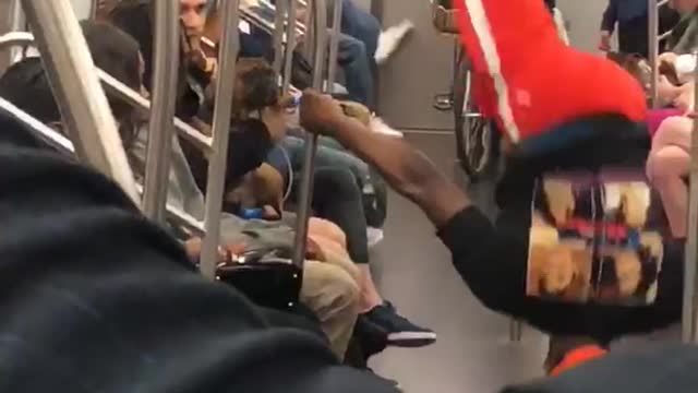 Brown french bulldog dancing on subway to music as guy in red dances