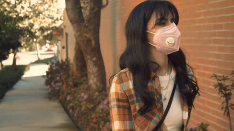 Woman wearing mask with her dog in the street