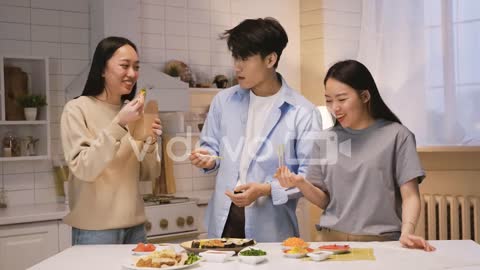 Three Japanese Friends Around The Kitchen Counter And Eating Japanse Food