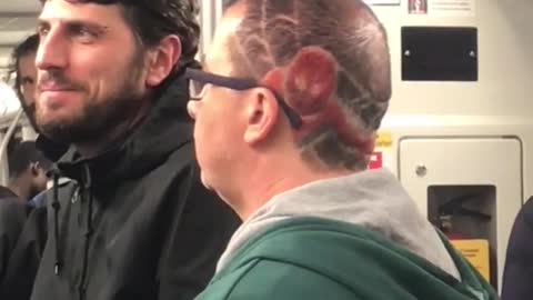 Man has red spiderman figure on hair head