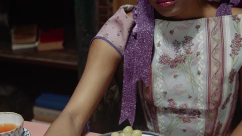 /a-woman-eating-grapes-with-her-cat-on-the-table