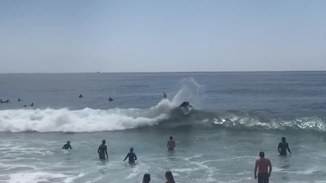 Little girl blue bathing suit gets knocked over by cute wave next to her friend