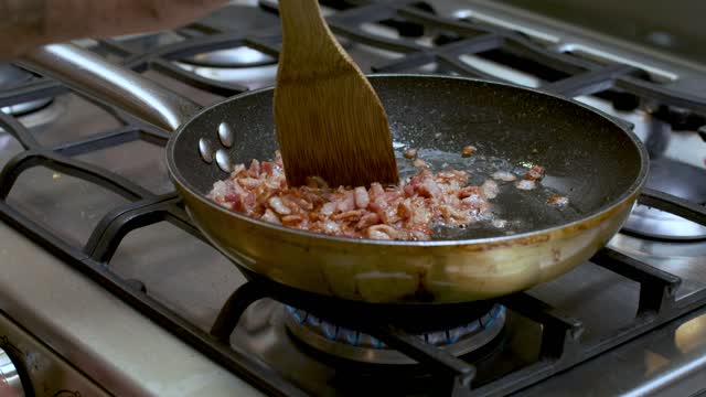 Frying diced bacon in a skillet