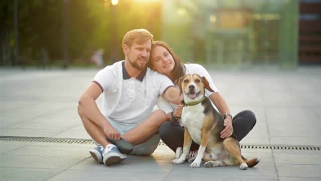 Outdoors Portrait of Couple in Love Enjoying with Beagle Dog Sitting on the City Square