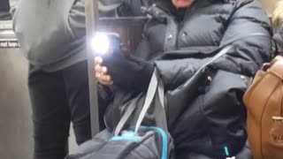 Mom using her phone on the subway accidentally leaves her flashlight on