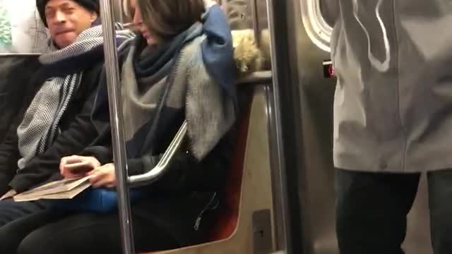 Man singing into his phone blue hat grey coat