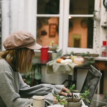 Young Woman Using Laptop while Having Breakfast
