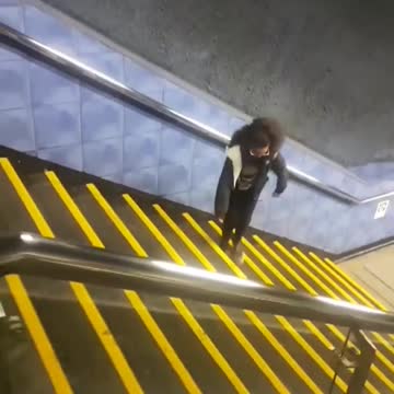 Girl glasses dancing up sideways yellow stairs train station