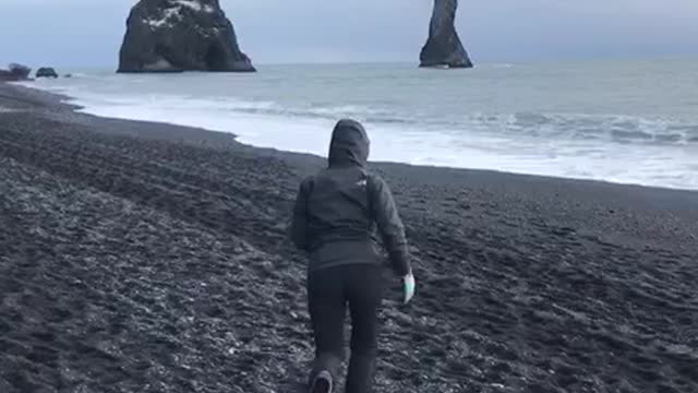 Woman runs on sand at the beach, jumps and falls