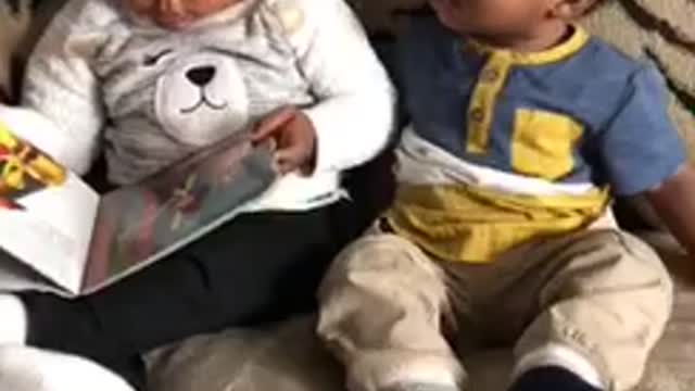 Big sister reads baby brother a story