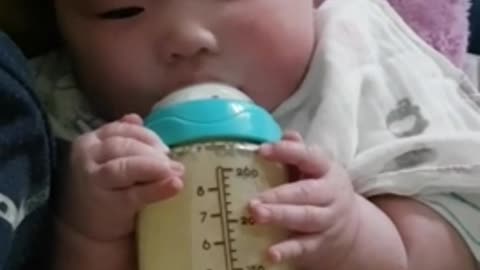 A baby holding and eating formula by himself