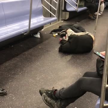 Guy lays on the floor in subway train