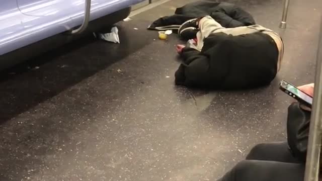 Guy lays on the floor in subway train