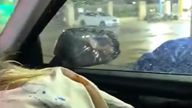 Woman struggles to close car door because of high winds