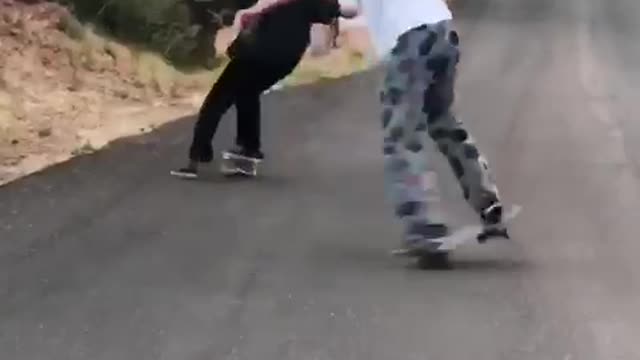 Two guys skateboard one falls on street