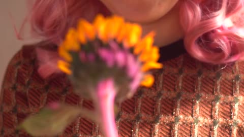 a-woman-with-a-pink-hair-is-smelling-a-sunflower