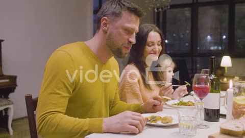 Husband And Wife Talking And Eating During A Family Dinner Sitting At Table At Home