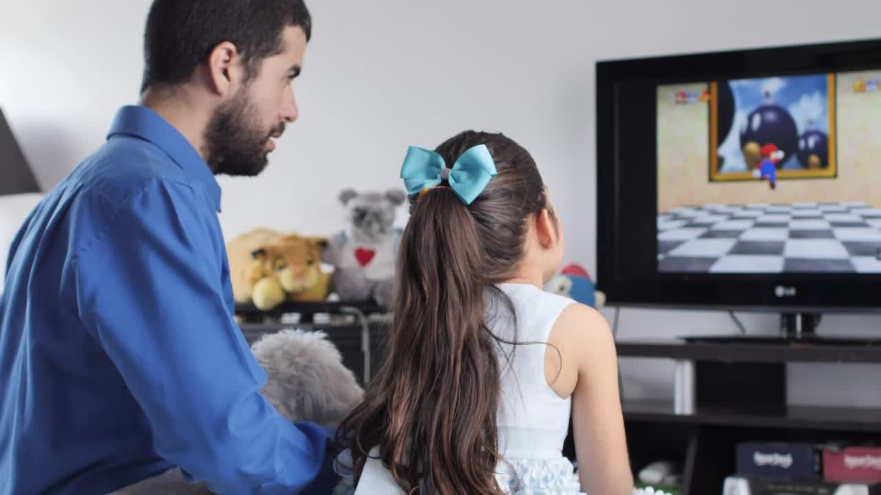Little girl playing video games with her father