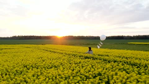 Walking on a flower field with a white balloon at sunset