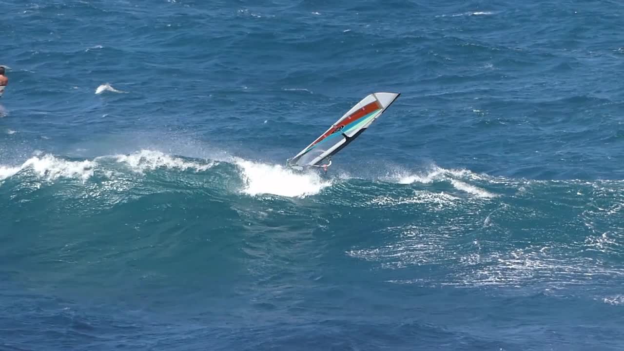 sailboarder performs a 360 degree forward flip off a wave on Maui's North Shore